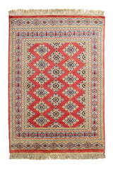 Vista superior de alfombra oriental con fondo rojo y patrón repetido de diamantes en azul claro, beige y negro.