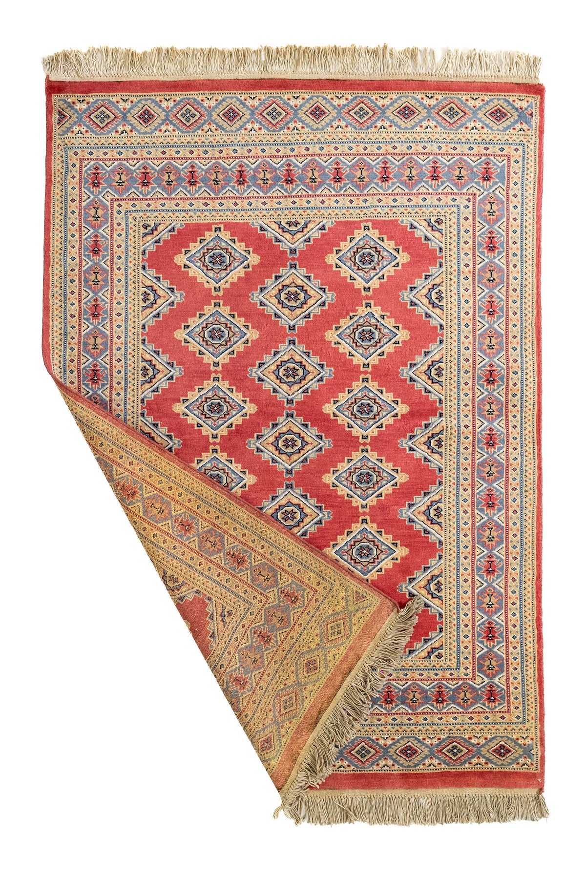 Alfombra artesanal parcialmente doblada mostrando el reverso tejido a mano con colores tierra y diseño simétrico.