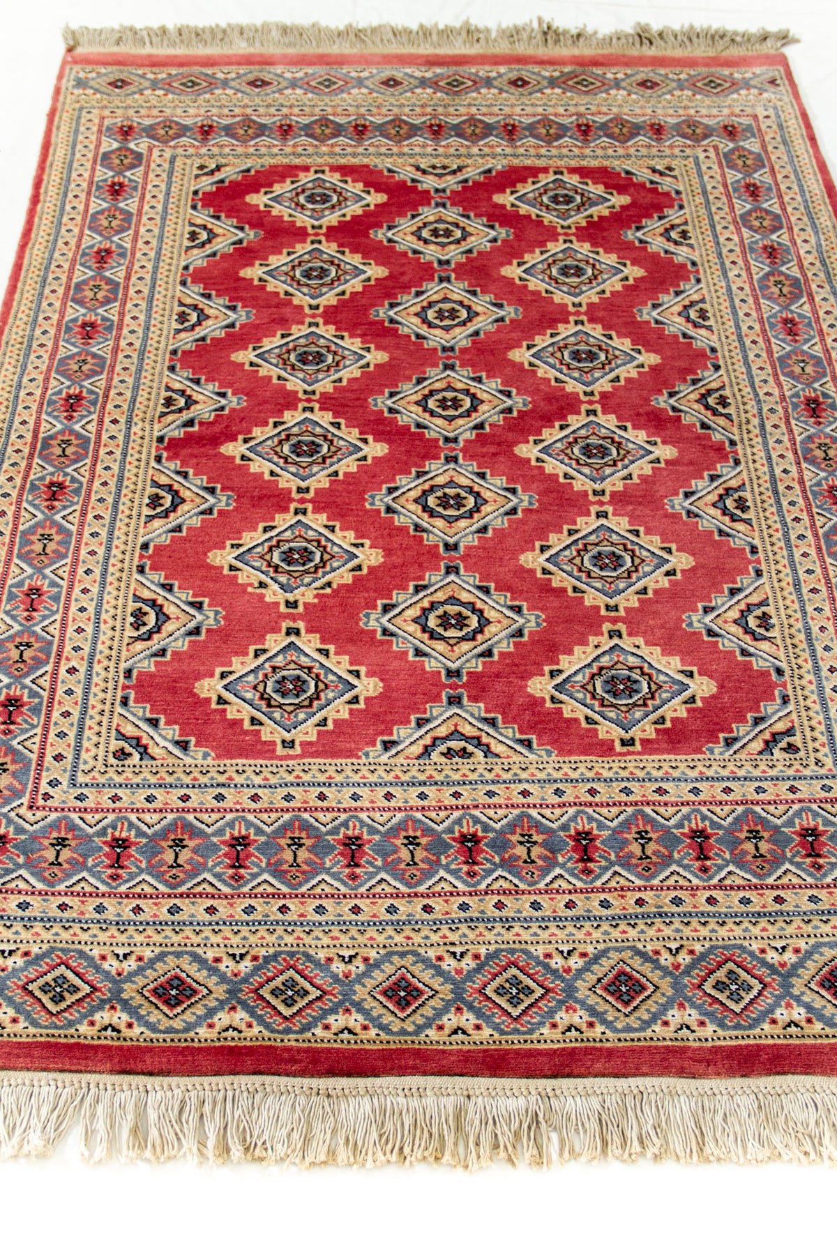 Vista en perspectiva de la alfombra mostrando la intensidad del fondo rojo y los detalles geométricos centrales.