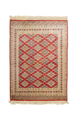 Vista completa de alfombra oriental con fondo rojo y patrones romboidales repetitivos en azul claro, beige y negro.