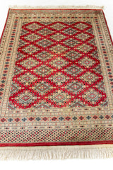 Vista en perspectiva de la alfombra extendida, resaltando la intensidad del rojo y los motivos centrales simétricos.
