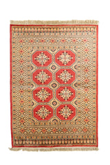 Vista completa de alfombra oriental con base roja y grandes figuras octogonales centrales en tonos beige, azul y negro.