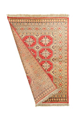 Alfombra parcialmente doblada mostrando tanto el frente como el reverso, resaltando la riqueza de sus detalles y el tejido fino.