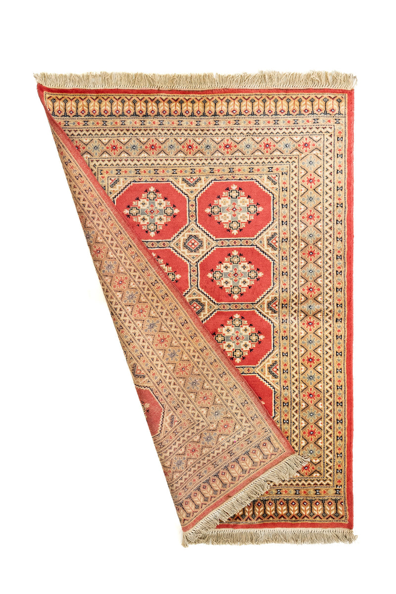 Alfombra parcialmente doblada mostrando tanto el frente como el reverso, resaltando la riqueza de sus detalles y el tejido fino.