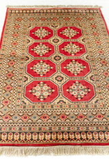 Vista en perspectiva de la alfombra extendida, destacando los patrones octogonales simétricos sobre el fondo rojo cálido.