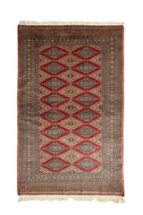 Vista completa de alfombra oriental con fondo en tonos terracota y figuras de rombos rojos, decorada con bordes geométricos.