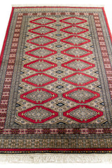 Vista en perspectiva de la alfombra extendida, resaltando los rombos alineados en el centro y las figuras negras dentro de ellos.