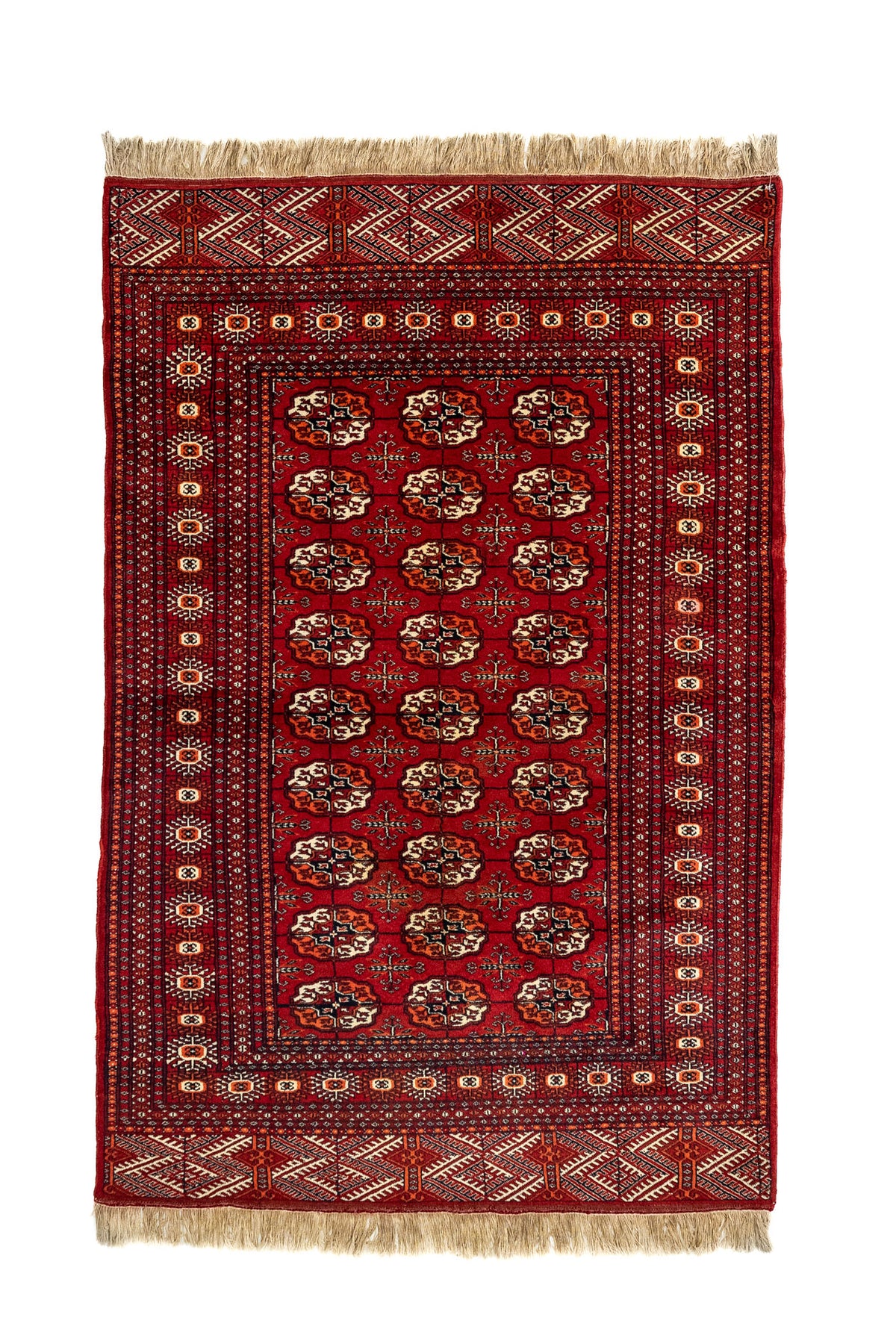 Vista completa desde arriba de una alfombra oriental roja con patrones repetitivos tipo "gul" en marfil y negro, y guardas decoradas con rombos.