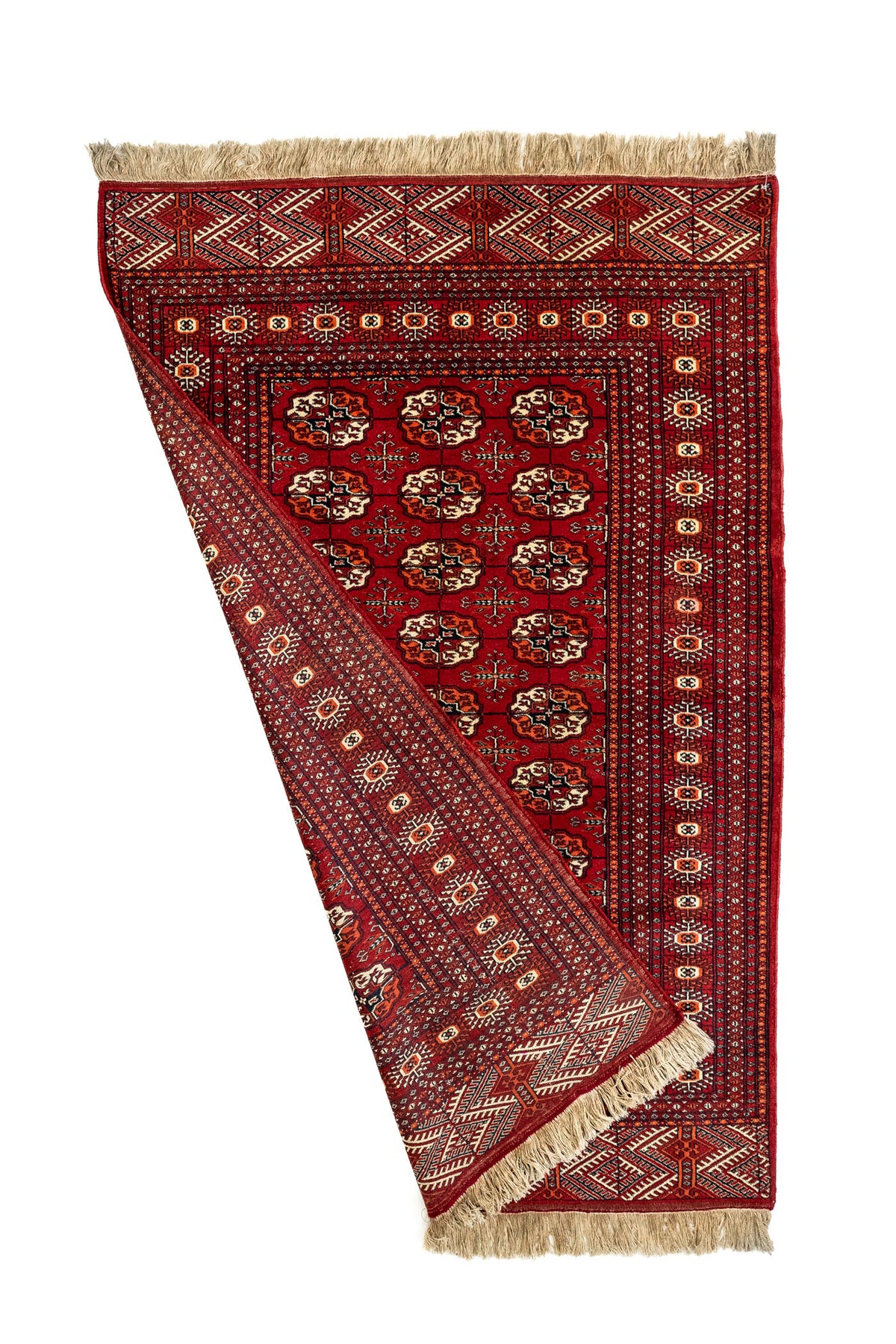 Imagen de la alfombra parcialmente doblada, mostrando el reverso del tejido, los flecos y los detalles del borde exterior.