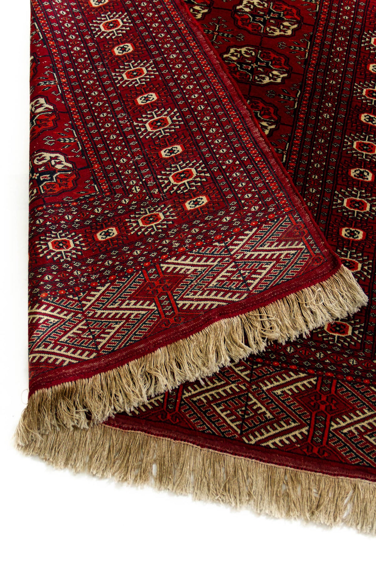 Primer plano de la esquina inferior de la alfombra con el borde doblado, destacando la calidad del tejido y los patrones geométricos.