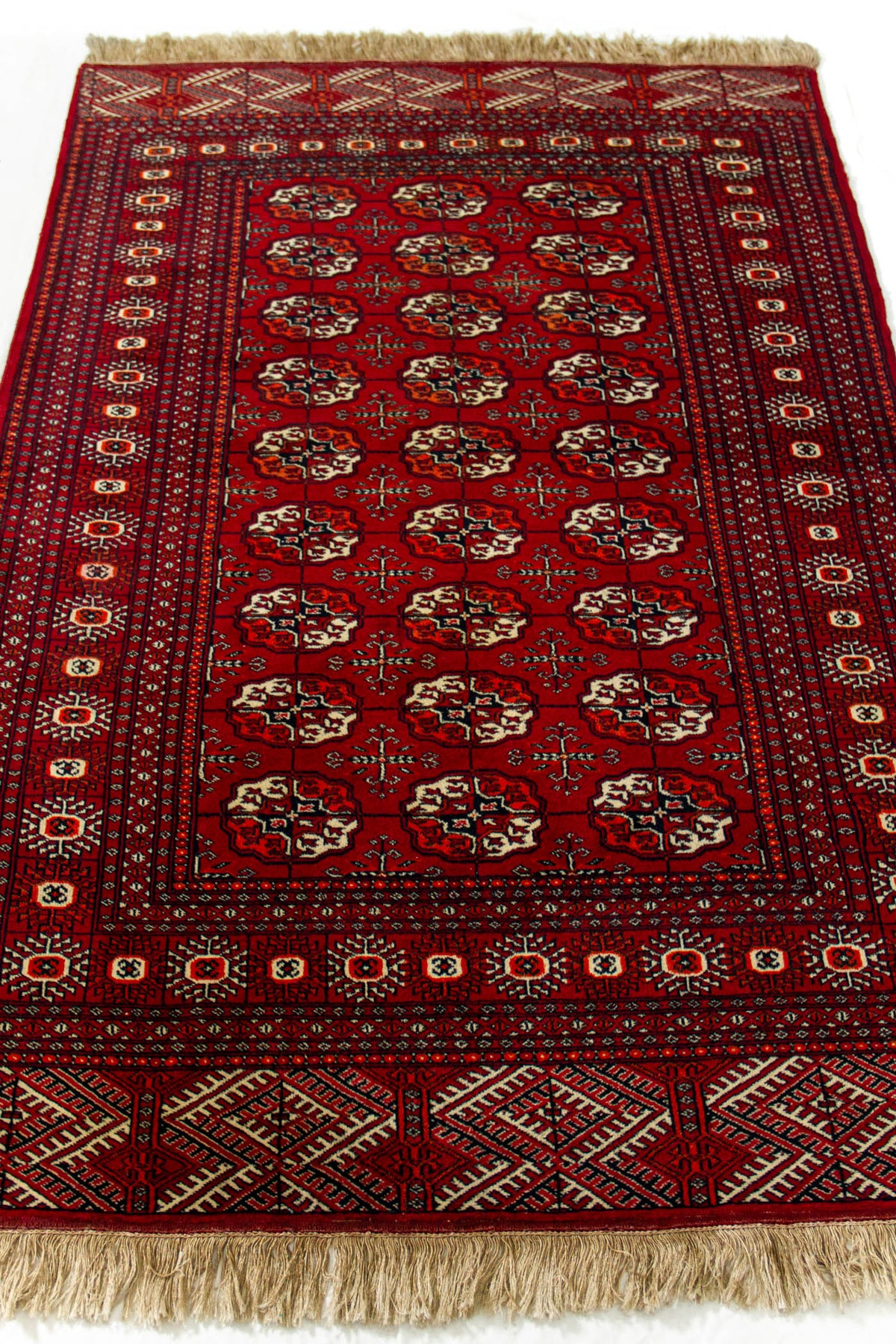 Imagen en perspectiva de la alfombra, enfocando el diseño central repetitivo y las guardas con motivos tribales.