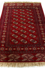 Imagen en perspectiva de la alfombra, enfocando el diseño central repetitivo y las guardas con motivos tribales.