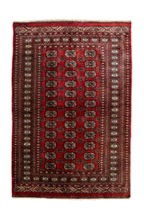 Vista superior completa de una alfombra oriental con fondo rojo y patrones repetitivos en negro y beige.