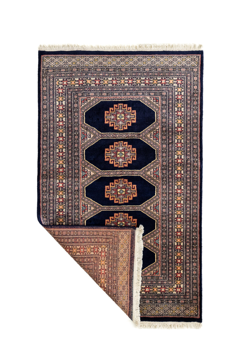 Alfombra oriental con una esquina doblada mostrando el reverso del tejido, destacando la precisión del diseño.