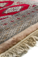Primer plano del borde lateral de la alfombra mostrando los patrones entrelazados y la textura del tejido.