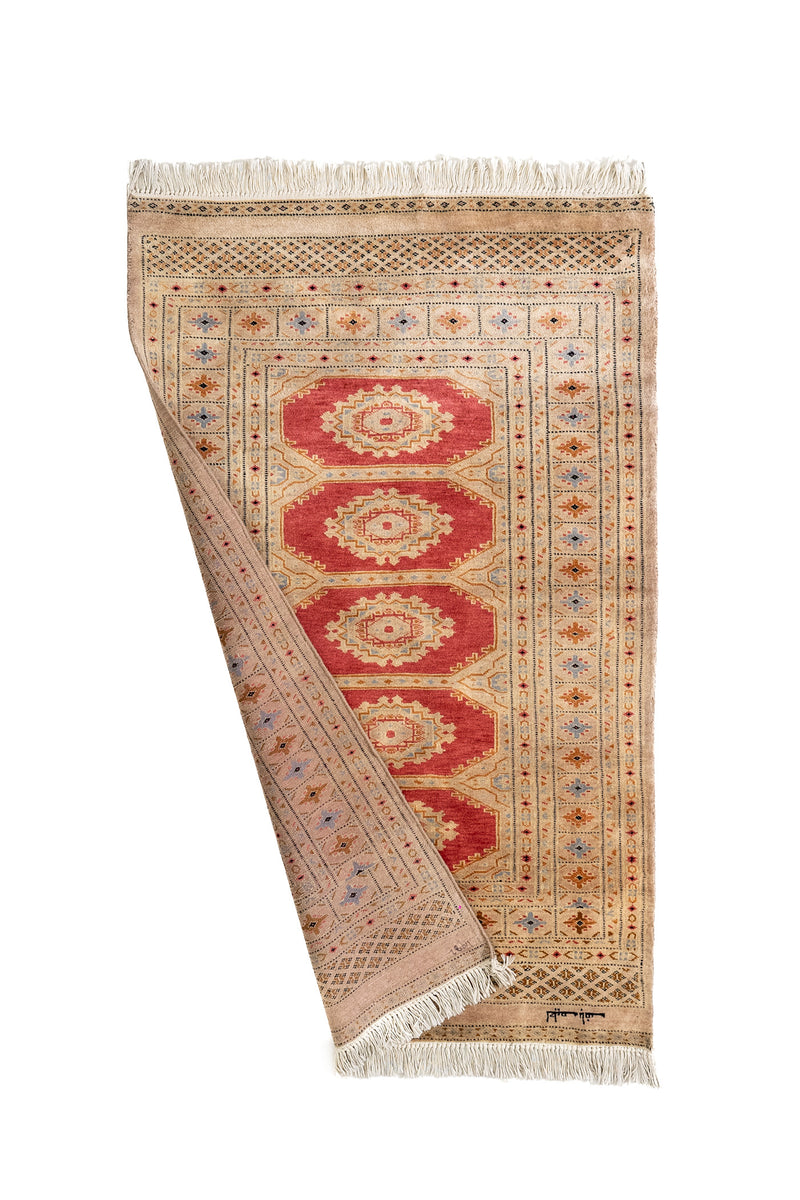 Alfombra oriental parcialmente doblada, mostrando el reverso tejido a mano.