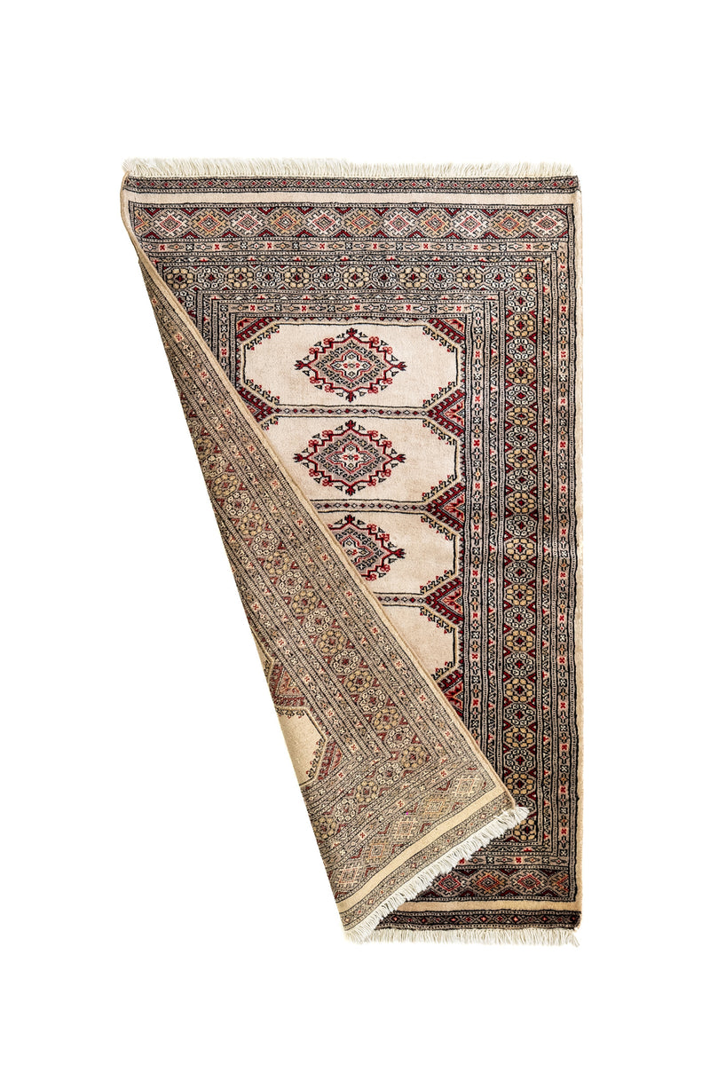 Alfombra oriental parcialmente doblada, mostrando el diseño en ambos lados.