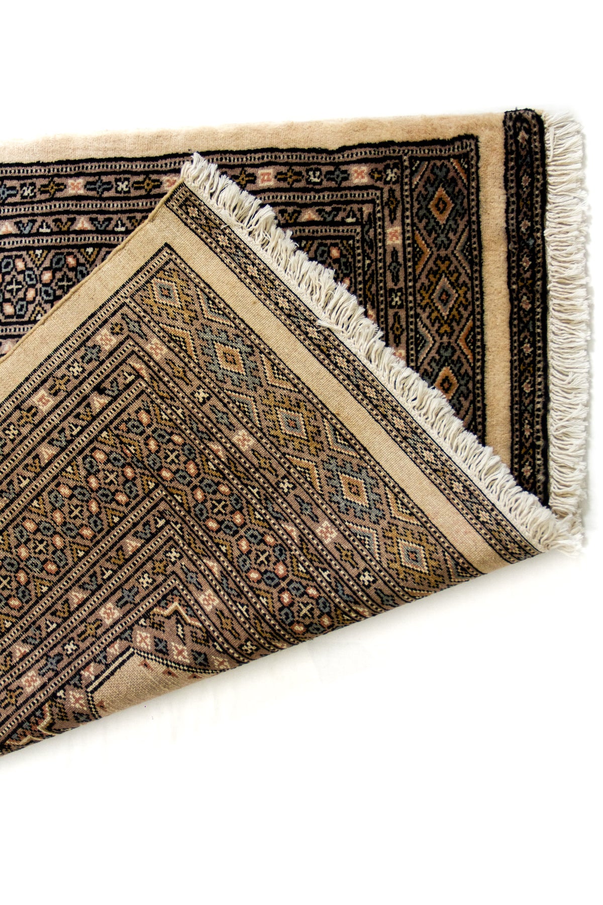 Detalle cercano del borde y el reverso de la alfombra mostrando la calidad del tejido y los flecos.