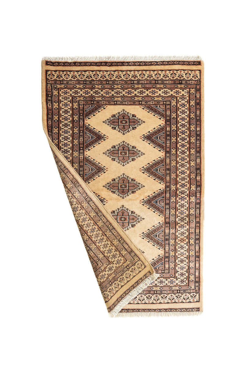 Alfombra doblada parcialmente mostrando su reverso y los detalles del borde artesanal.