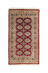 Vista completa de una alfombra oriental con fondo rojo oscuro y patrones florales geométricos en disposición de rombos.