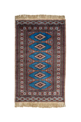 Vista completa de alfombra oriental con fondo azul vibrante y medallones geométricos en tonos beige, rojo y negro.
