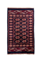 Vista completa de una alfombra oriental con fondo azul oscuro y patrones geométricos en tonos rojo intenso y beige.