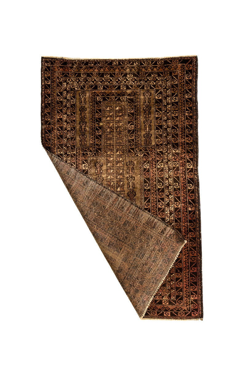 Alfombra doblada en una esquina, revelando el reverso de la pieza y la continuidad del patrón artesanal.