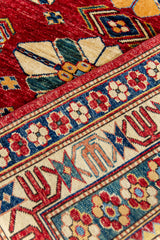 Detalle en primer plano de los motivos florales y geométricos en el borde de la alfombra con contraste de colores vivos.