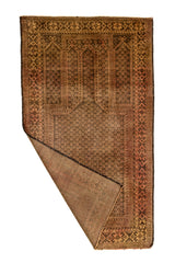 Alfombra oriental vista parcialmente doblada, mostrando el reverso y los detalles de su entramado artesanal.