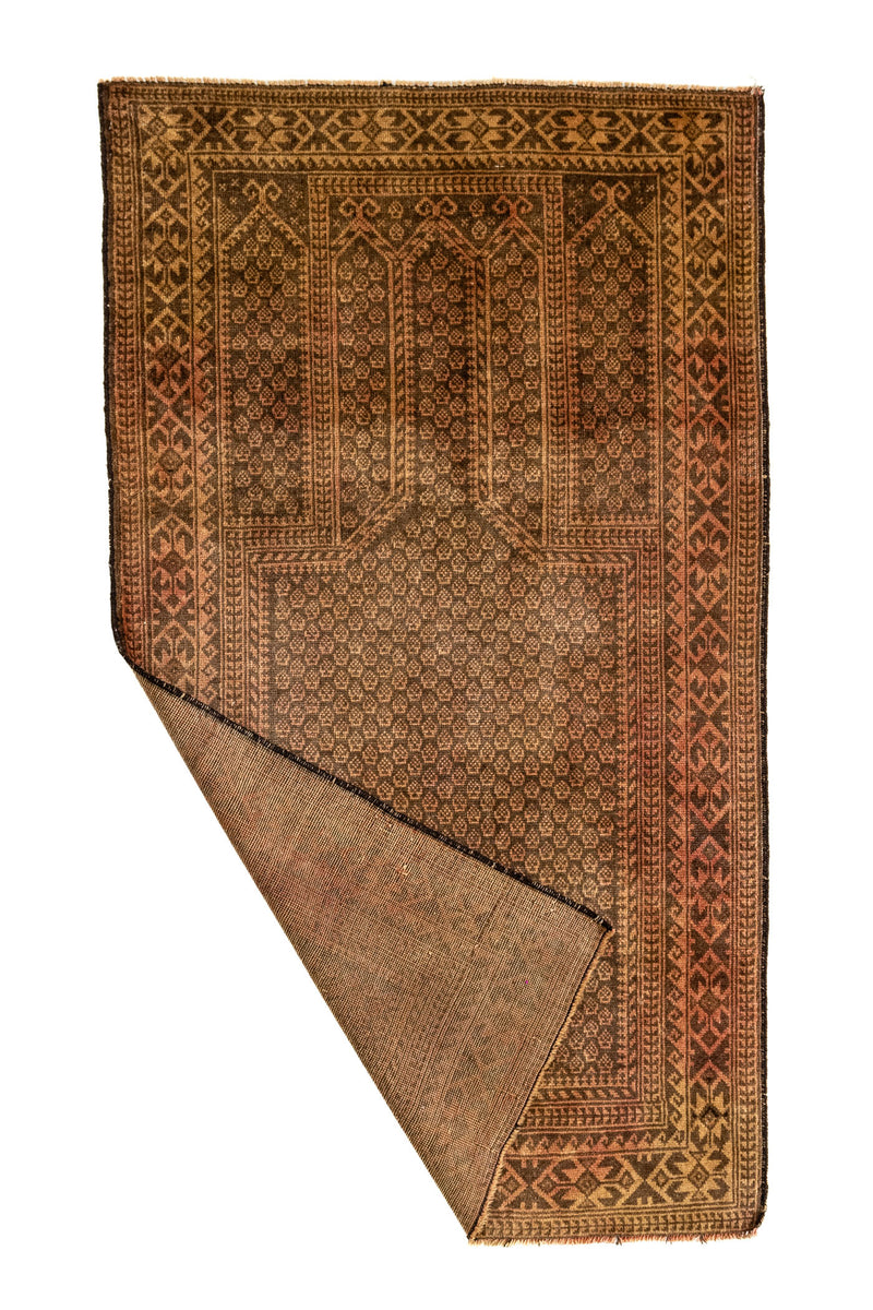 Alfombra oriental vista parcialmente doblada, mostrando el reverso y los detalles de su entramado artesanal.