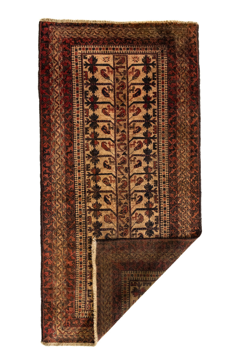 Alfombra oriental mostrada parcialmente doblada en una esquina para revelar su reverso, destacando su textura tejida artesanalmente.