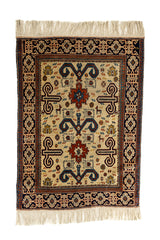 Vista completa de alfombra con fondo beige claro, motivos simétricos en rojo, azul oscuro y bordes en negro con patrones florales.