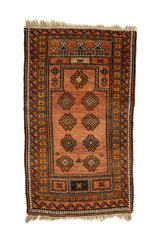 Vista superior de una alfombra oriental con fondo terracota y motivos romboidales simétricos en tonos amarillo y negro, enmarcada por una guarda geométrica.