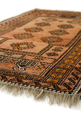 Toma lateral enfocada en la textura de la alfombra, destacando los flecos en lana natural y los colores cálidos predominantes.