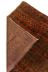 Detalle ampliado del reverso de la alfombra, mostrando las tramas del tejido en tonos rojo y marrón rojizo.