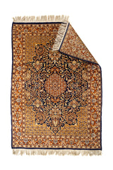 Alfombra oriental con una esquina doblada, mostrando el reverso y los detalles del entramado fino en tonos azules y beige.