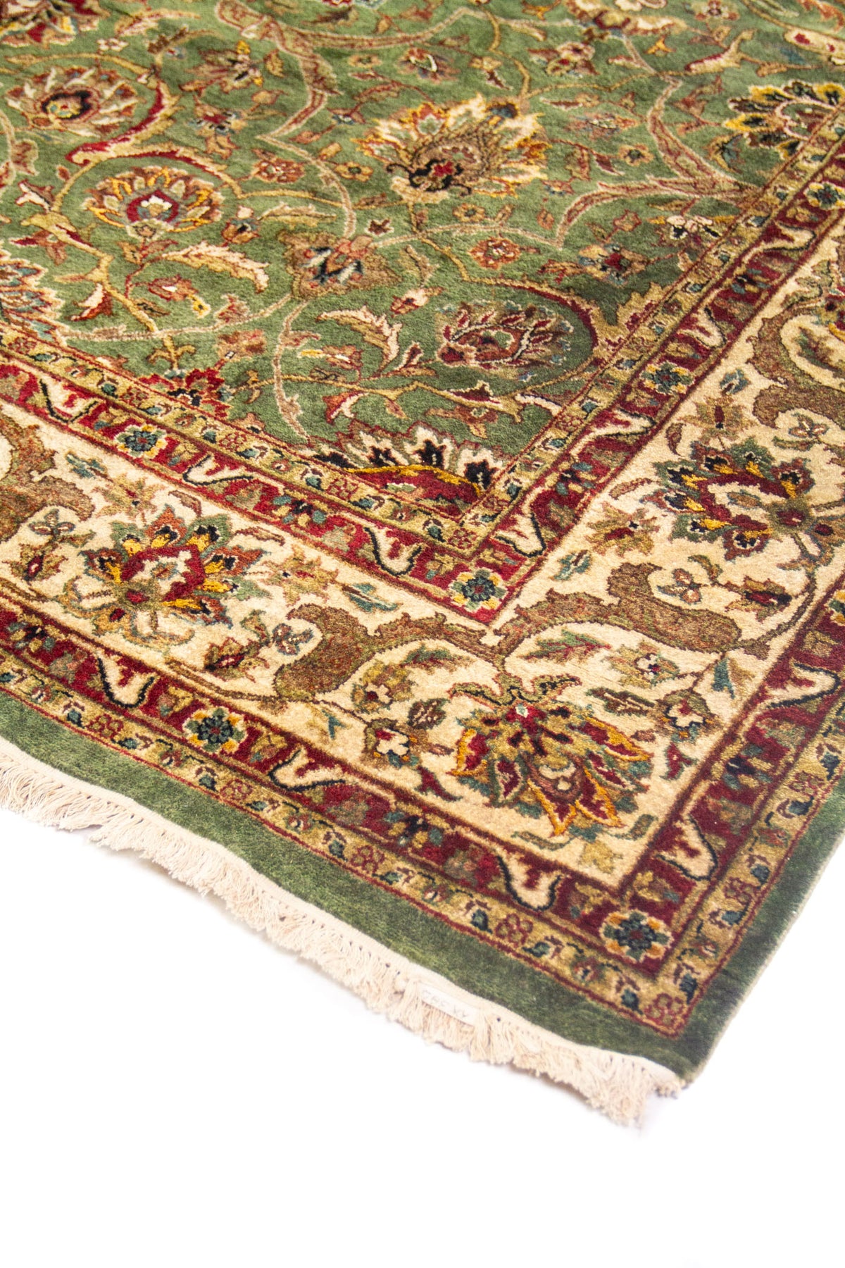 Vista en ángulo de alfombra verde con franja floral crema y acentos rojos y dorados.