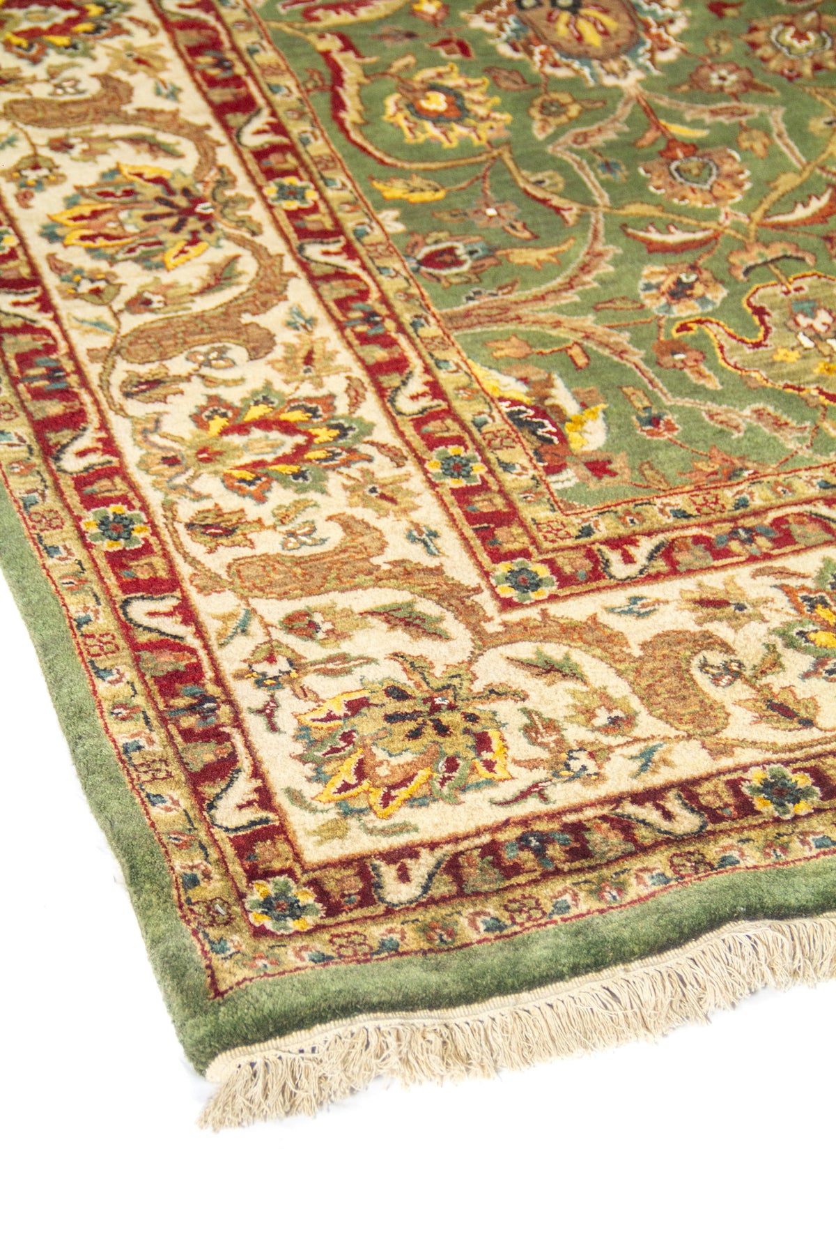 Primer plano de la guarda de alfombra verde, con arabescos florales y bordes finos en rojo y beige.