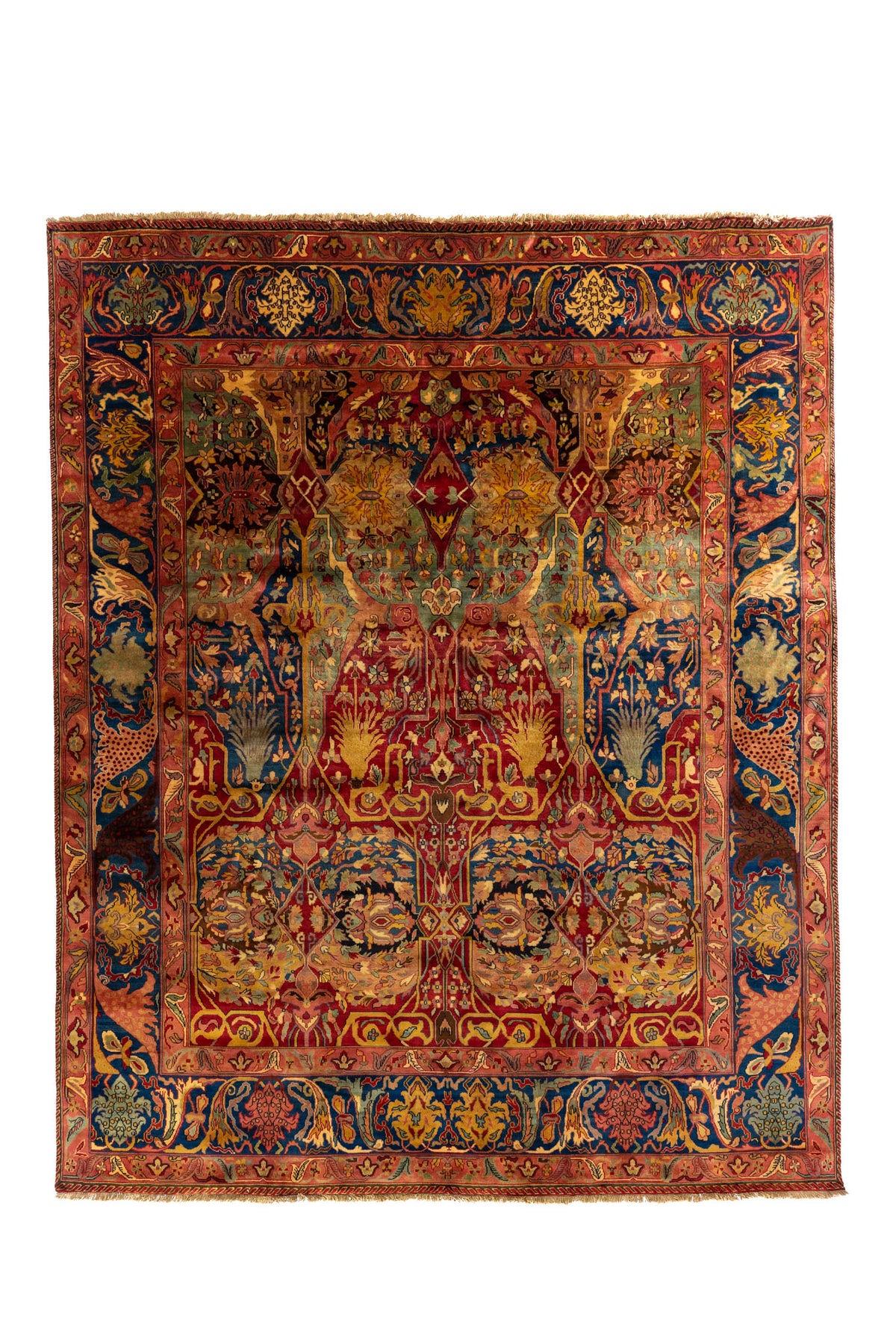 Detalle de alfombra oriental doblada con guarda azul y rosado, motivos florales y flecos beige.