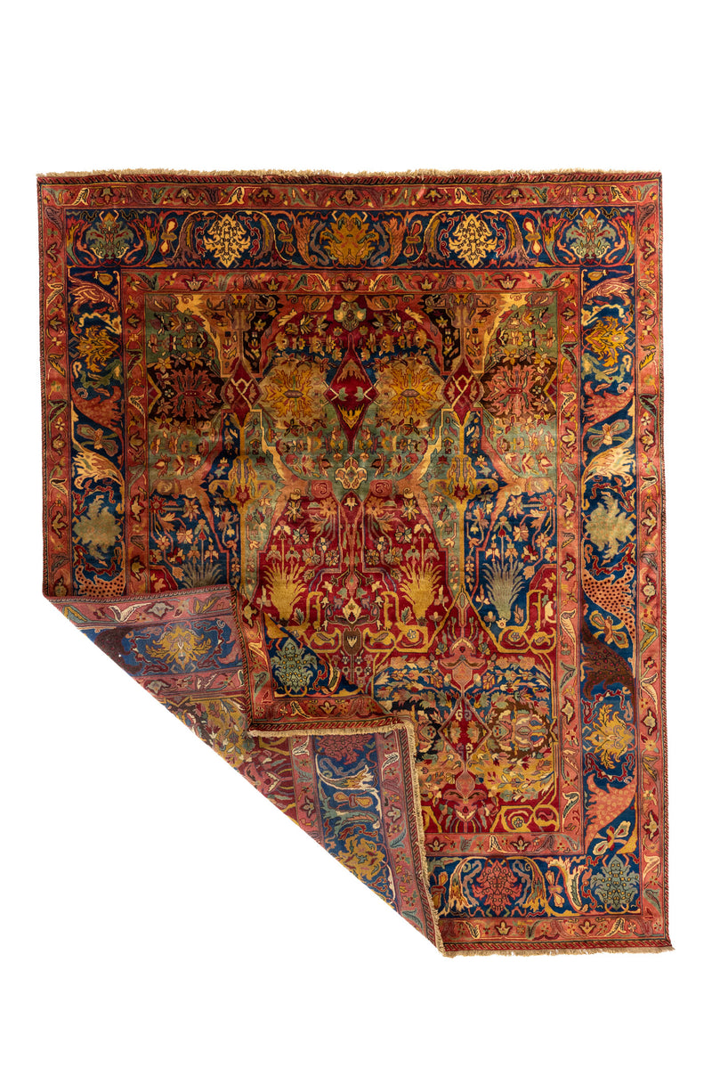 Alfombra clásica de gran formato con diseño ornamental en tonos rojo, azul, rosado, y composición central simétrica.