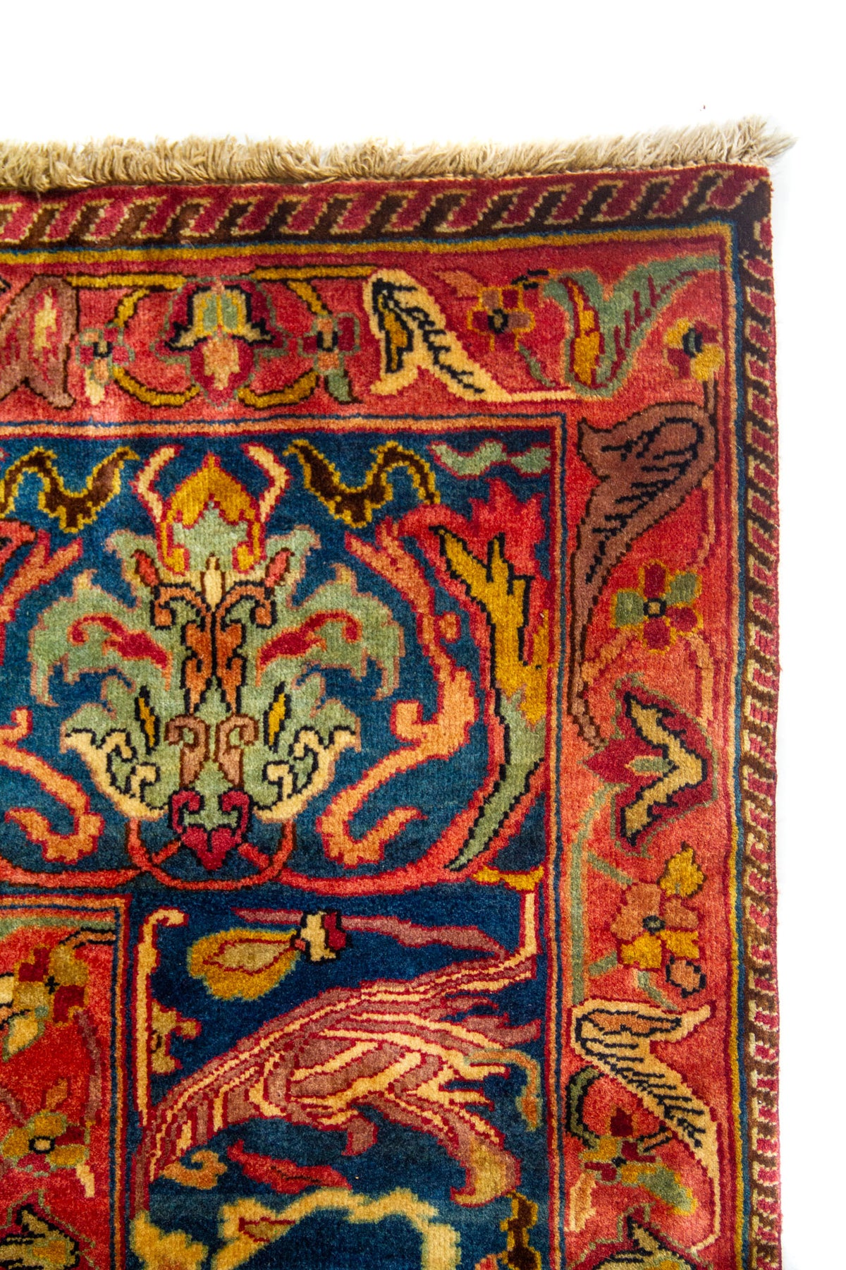 Vista en ángulo de alfombra clásica con motivos ornamentales complejos en tonos azul, rosado, rojo y dorado.