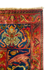 Vista en ángulo de alfombra clásica con motivos ornamentales complejos en tonos azul, rosado, rojo y dorado.
