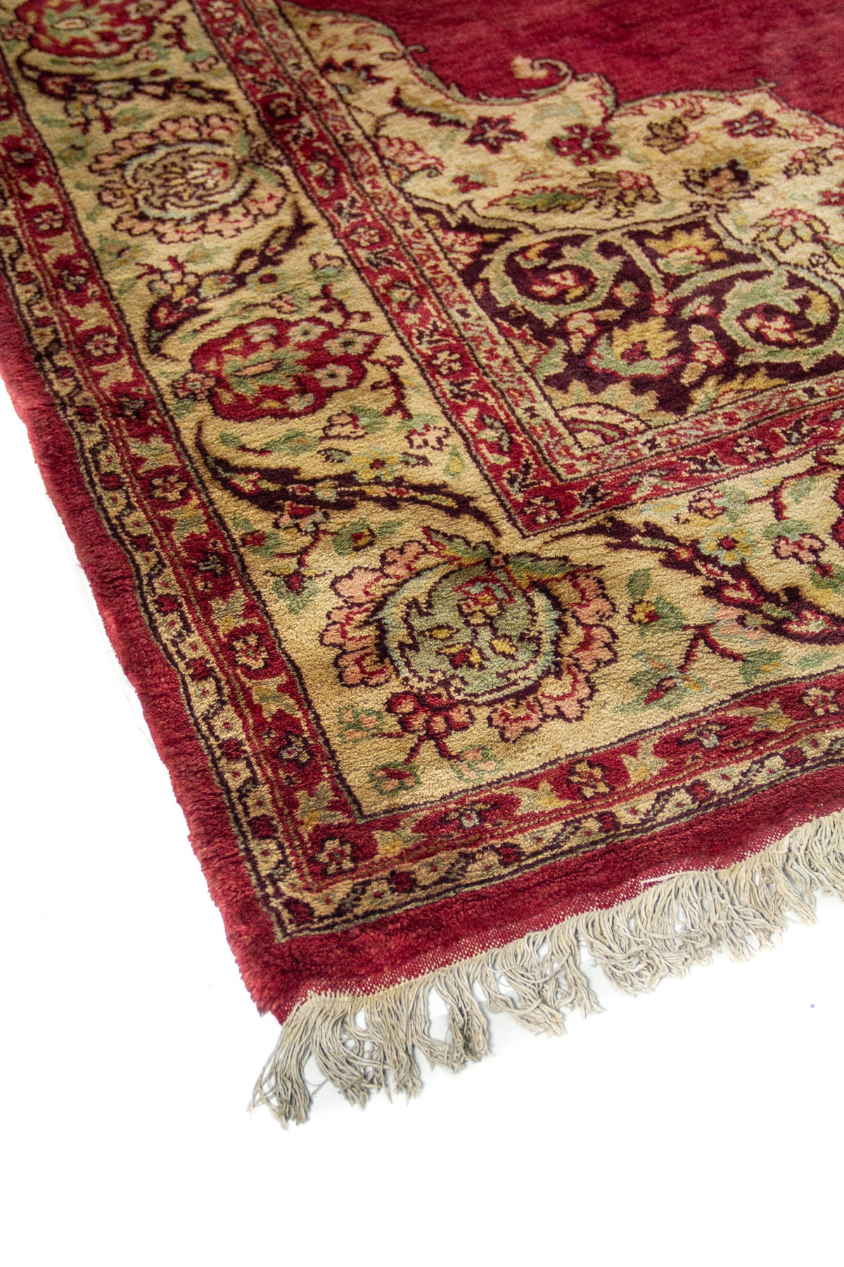 Vista en ángulo de la alfombra roja burdeos; se aprecia la guarda floral beige y el contraste del marco interior.