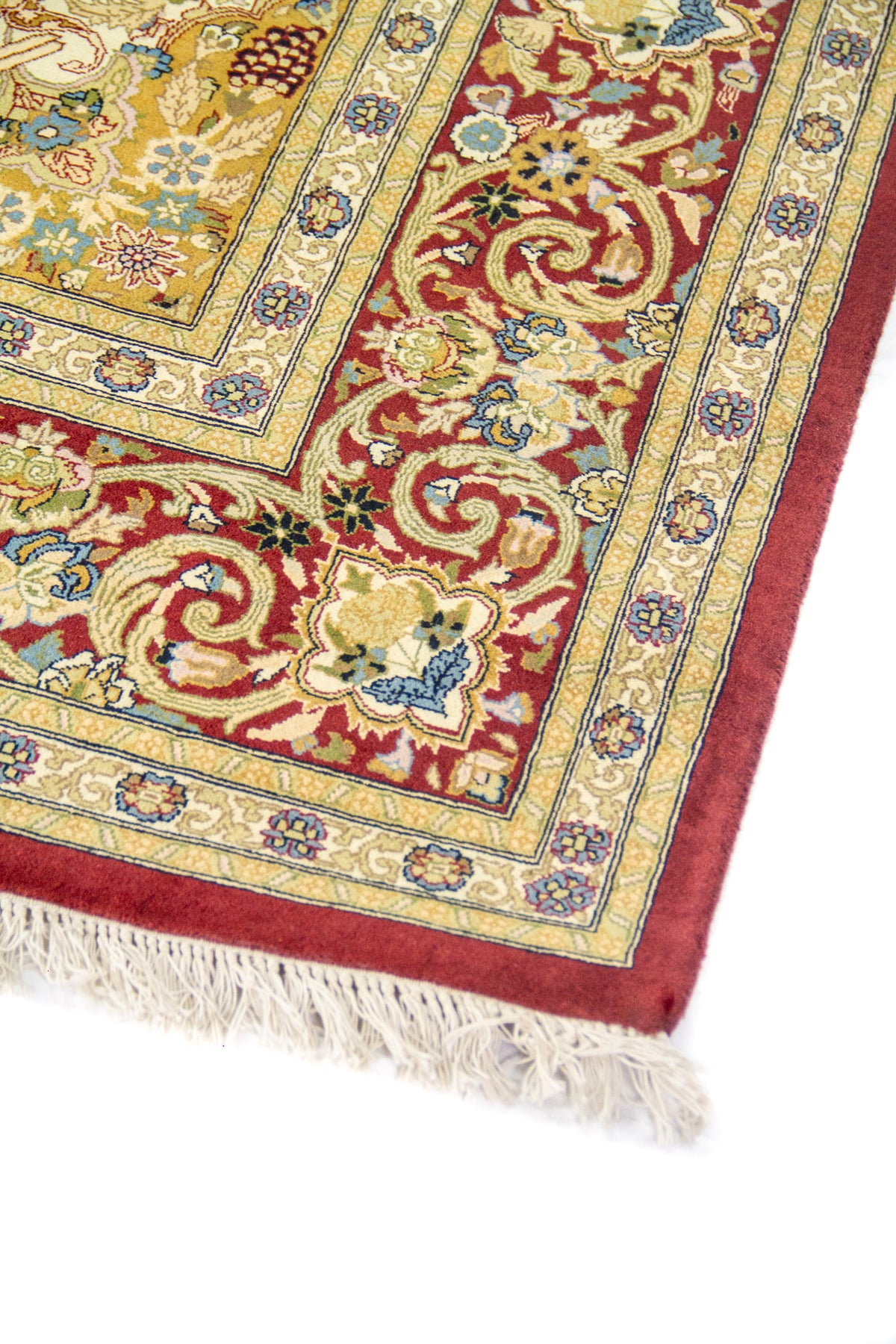 Detalle del borde rojo con arabescos y franjas florales en beige, azul y verde, vista en perspectiva.
