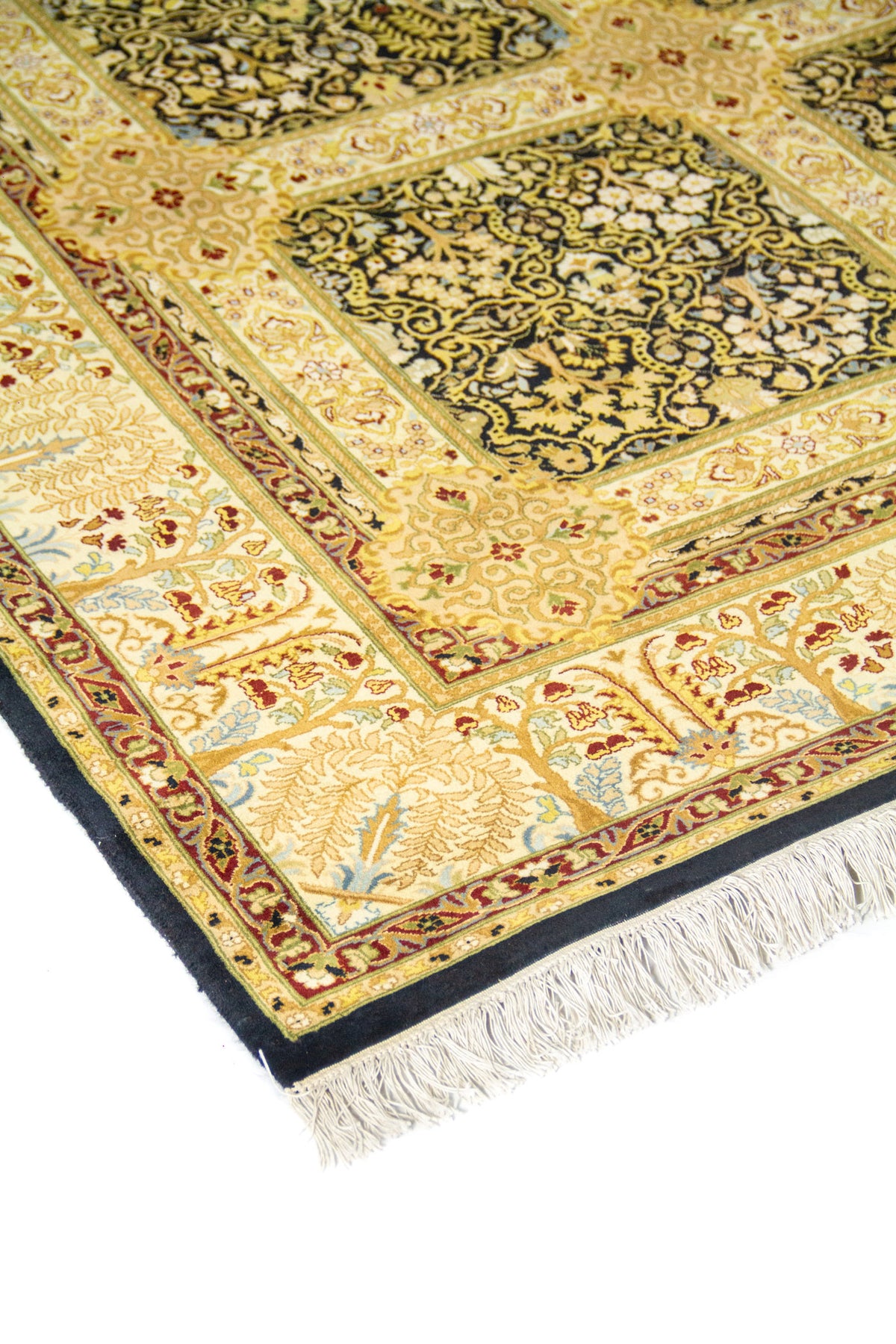 Primer plano de esquina de alfombra clásica con diseño floral ornamental, borde marfil y marco exterior oscuro con flecos.