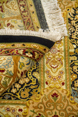 Detalle de alfombra doblada mostrando textura, flecos y diseño ornamental de inspiración persa en tonos beige, dorado y negro.