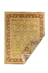 Alfombra clásica floral en tonos verde oliva y rojo vino con una esquina doblada, mostrando el reverso y el grosor del tejido.