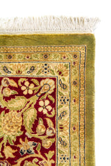 Detalle de esquina superior de alfombra oriental con flecos blancos, borde exterior verde oliva y guarda floral rojo vino con motivos beige.