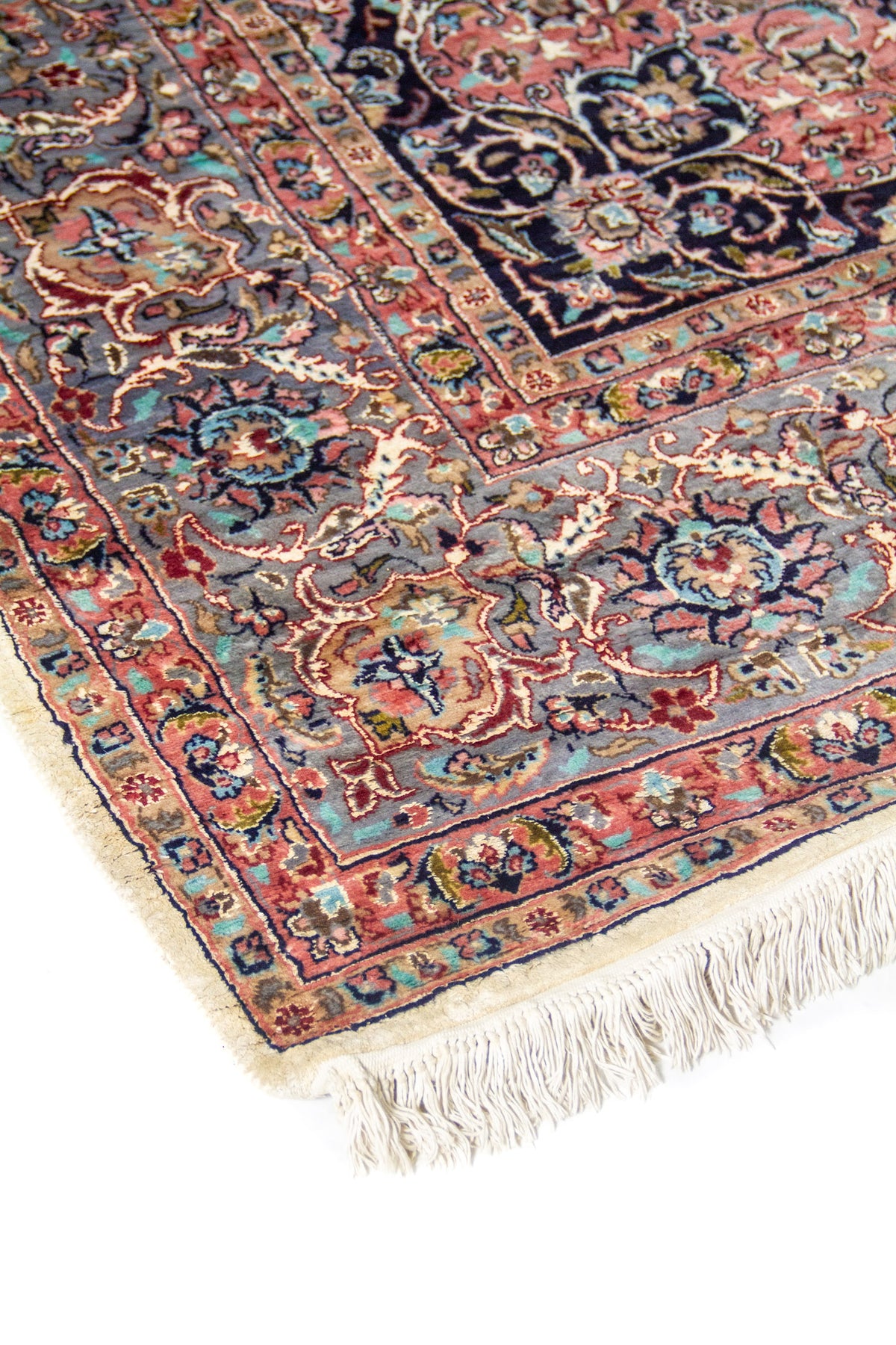 Primer plano de guarda ornamental con motivos florales en tonos azul, rosado y beige, acabado con flecos claros.