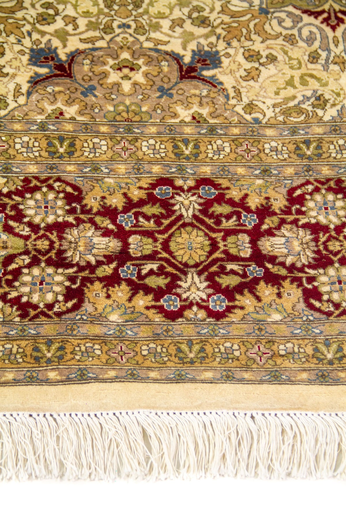 Primer plano de la guarda roja vino con flores estilizadas y flecos marfil en alfombra de estilo clásico.